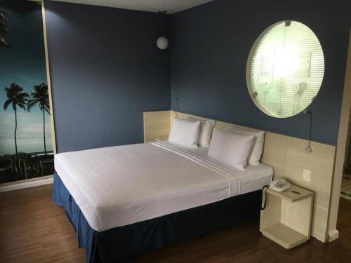 - une chambre avec un grand lit et un mur bleu dans l'établissement Flat no Mercure Navegantes, à Récife
