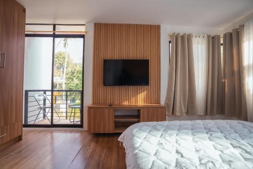 een slaapkamer met een bed, een televisie en een balkon bij Riverduplex - Luxury duplex at a fair price in Dauis