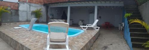 een zwembad met een stoel en een tafel en twee stoelen bij Recanto caçapava in Caçapava