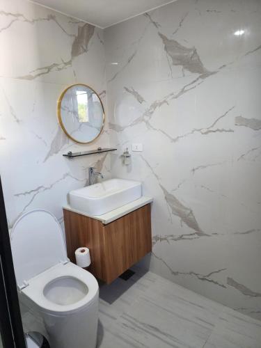 een badkamer met een toilet, een wastafel en een spiegel bij Riverduplex - Luxury duplex at a fair price in Dauis