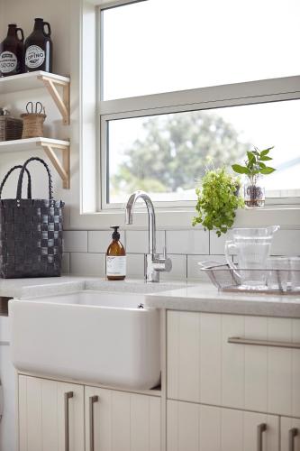 a white kitchen with a sink and a window at Matarangi Beach Retreat in Matarangi