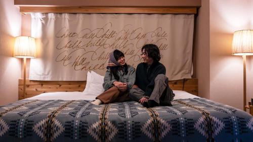 a man and a woman sitting on a bed at UNWIND Hotel & Bar 札幌 in Sapporo