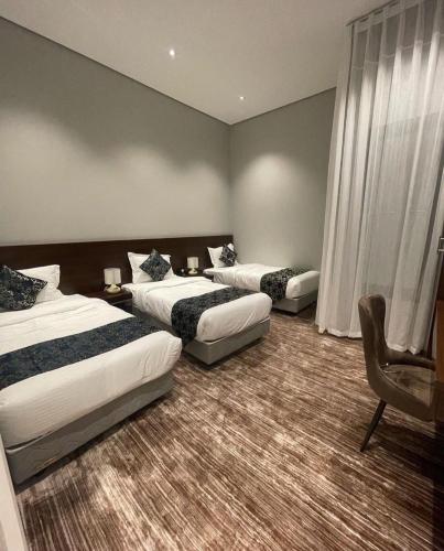 una habitación de hotel con 2 camas y una silla en REST IN 2, en Unaizah