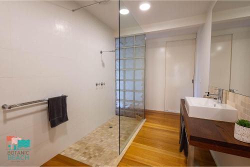 a bathroom with a glass shower and a sink at Botanic Beach in Warrnambool