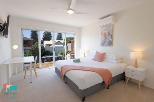 a bedroom with a bed and a desk and a window at Botanic Beach in Warrnambool