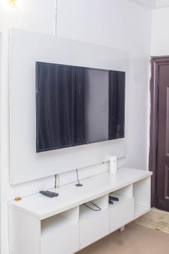 um centro de entretenimento branco com uma televisão na parede em BLESSED HOME em Lagos