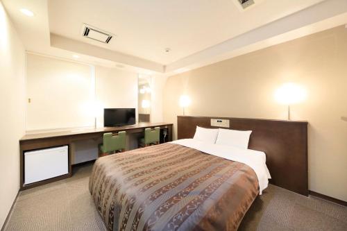 a bedroom with a bed and a desk and a television at Hotel Shinjukuya in Machida