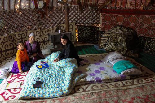 um grupo de pessoas sentadas numa cama numa tenda em Yurt Stay Family Khansar em Nurota