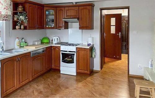 a kitchen with wooden cabinets and a white stove top oven at Amazing Home In Trynisze Moszewo in Ciechanowiec