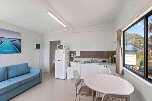 a living room with a blue couch and a table at Beach Cabins Merimbula in Merimbula
