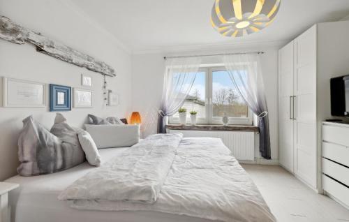 een witte slaapkamer met een groot bed en een raam bij Pet Friendly Apartment In Carolinensiel With House A Panoramic View in Carolinensiel