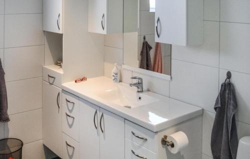een witte badkamer met een wastafel en een spiegel bij Beautiful Home In Brekkest With Lake View 