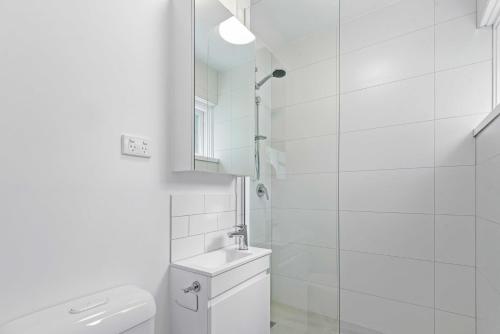 a white bathroom with a toilet and a mirror at Stunning 1-Bed Ground Floor Unit with Front Yard in Melbourne