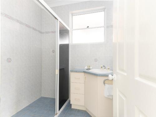 a white bathroom with a sink and a shower at 21 Melaleuca Drive -LJHooker Yamba in Yamba