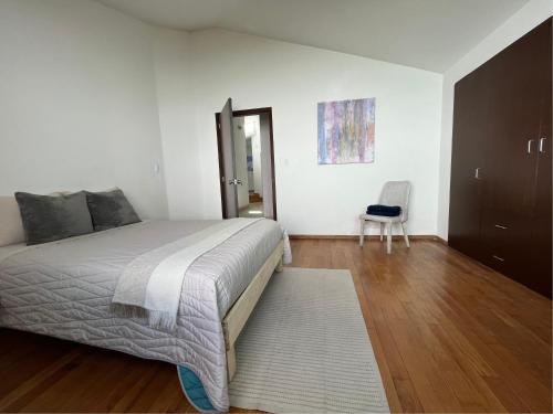 um quarto com uma cama grande e uma cadeira em La Casa del Agua Puebla em Acatepec