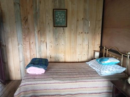 Cama en habitación de madera con 2 almohadas en Posada Turistica Los Joseph en La Isla