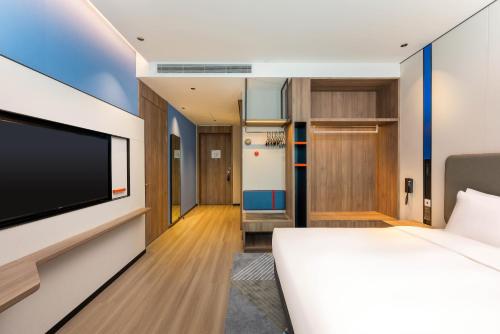 a hotel room with a bed and a flat screen tv at Holiday Inn Express Liaocheng ETDZ, an IHG Hotel in Liaocheng