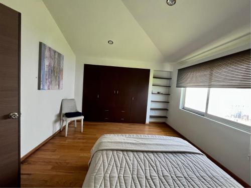 a bedroom with a bed and a window and a chair at La Casa del Agua Puebla in Acatepec