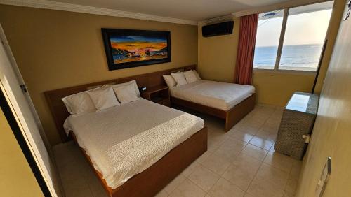 um pequeno quarto com 2 camas e uma janela em Apartamento 1403 Edificio Karey El Rodadero em Santa Marta