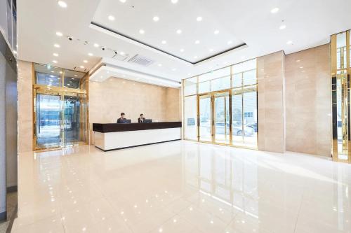 a lobby with two people sitting at a counter in a building at Gold Coast Hotel Incheon in Incheon