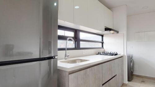 een witte keuken met een wastafel en een raam bij Your Central Base near Unicentro in Bogota