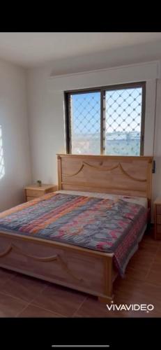 a bedroom with a wooden bed with two windows at مزرعة كراون in Umm el ‘Amad