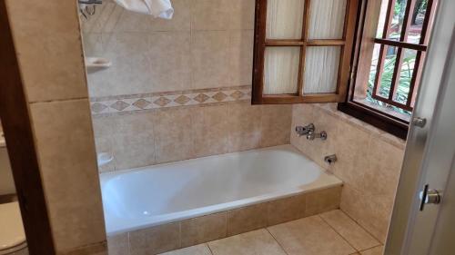 Hotel Cabañas del Leñador في بويرتو إجوازو: حوض استحمام أبيض في حمام مع نافذة