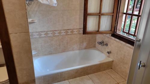 a white bath tub in a bathroom with a window at Hotel Cabañas del Leñador in Puerto Iguazú