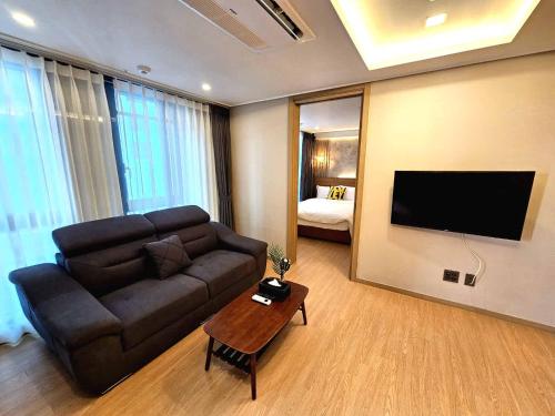 ein Wohnzimmer mit einem Sofa und einem Flachbild-TV in der Unterkunft Raviens라비앙즈 in Busan