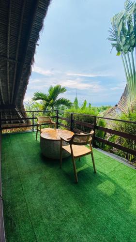 a patio with a table and chairs on the grass at Balangan Sea View Bungalow in Jimbaran