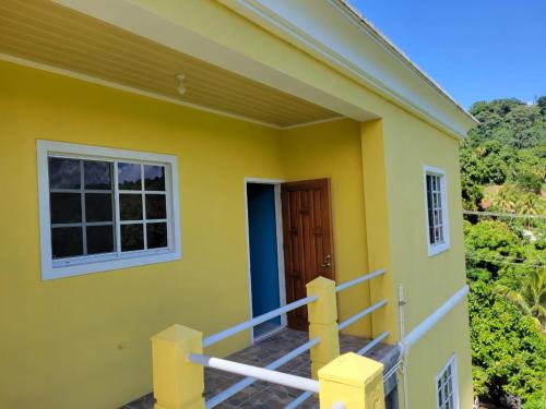 a yellow house with a balcony with a door at Spring View Apartment in Belmont
