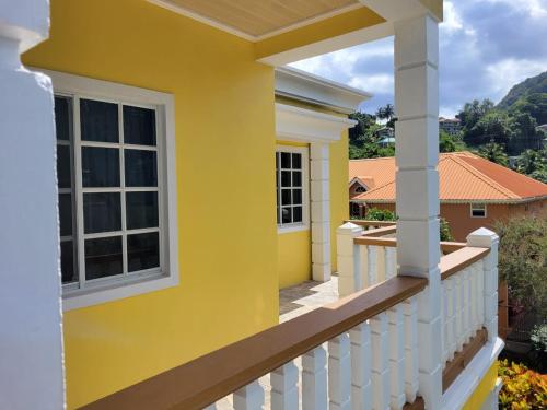 a yellow house with a white fence and a balcony at Spring View Apartment in Belmont