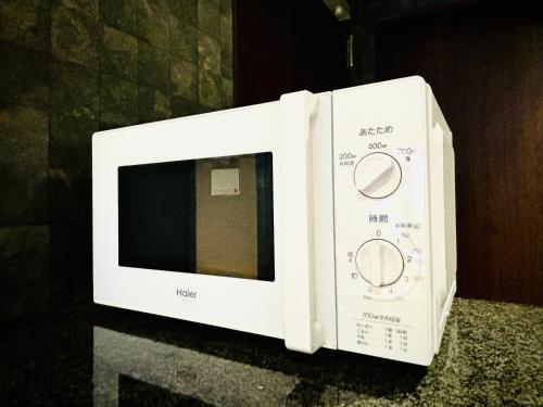 a white microwave oven sitting on top of a counter at 嵐 Hotel Arashi 難波店 in Osaka