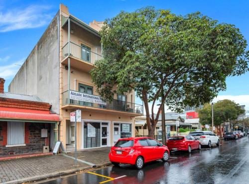 a red car parked in a parking lot in front of a building at Studio B - Wright Lodge in Adelaide