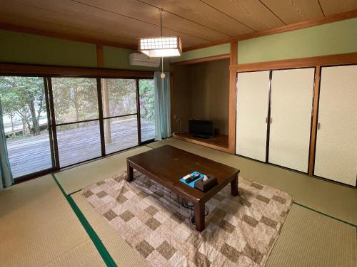 a living room with a coffee table in a room with windows at Yamamizuki in Shimanto