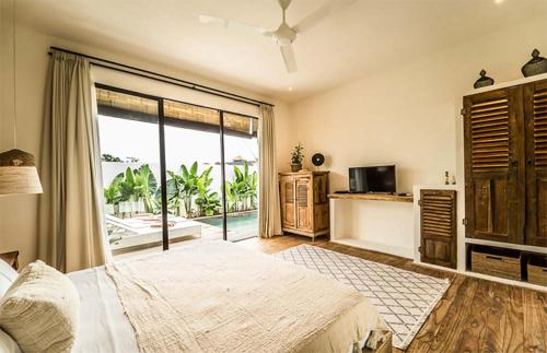 a bedroom with a large bed and a large window at Villa Kosibali by Optimum Bali Villas in Kerobokan