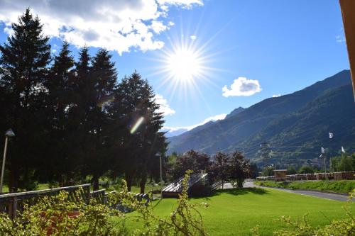 a view of a green field with the sun in the sky at Hotel Garni Pegrà in Ponte di Legno