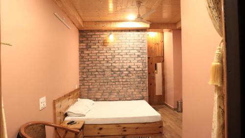 a bed in a room with a brick wall at Rustic Roots Home Stay in Nagar