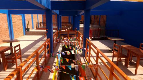 een kamer met houten tafels en stoelen en kleurrijke vlaggen bij Raymi House Hostel in Arica