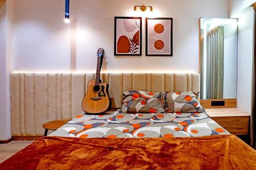 um quarto com uma cama com uma guitarra na parede em Swati Homestays em Ahmedabad