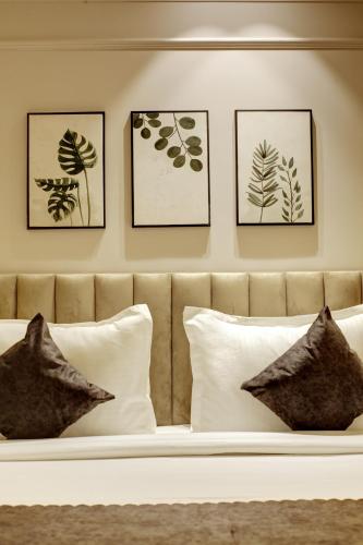 a bed with four framed pictures on a wall with pillows at Saltstayz Premier - Near Golf Course Road & Sector 57 in Gurgaon
