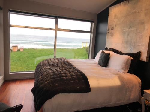 a bedroom with a large bed and a large window at Cloud 9 in Karitane
