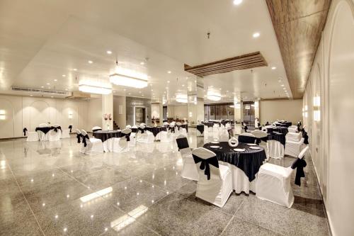 a banquet hall with black and white tables and chairs at Saltstayz Premier - Near Golf Course Road & Sector 57 in Gurgaon