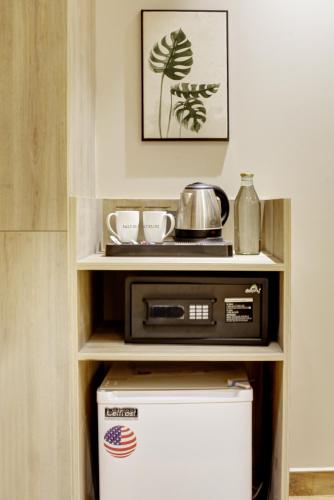 a microwave in a shelf with a pot on top of it at Saltstayz Premier - Near Golf Course Road & Sector 57 in Gurgaon