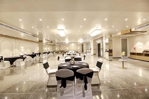 a banquet hall with black and white tables and chairs at Saltstayz Premier - Near Golf Course Road & Sector 57 in Gurgaon
