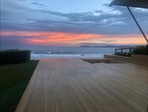 a wooden boardwalk next to the ocean at sunset at Cloud 9 in Karitane