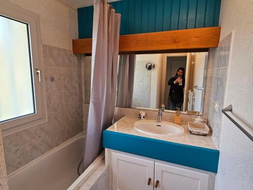 une personne prenant une photo d'une salle de bains avec lavabo dans l'établissement Appartement Centre-Ville Calme avec Balcon et Garage - Saint-Georges-de-Didonne - FR-1-550-73, à Saint-Georges-de-Didonne