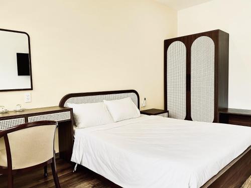 a bedroom with a bed and a desk with a mirror at Han Riverine Hotel & Cafeteria DaNang in Da Nang