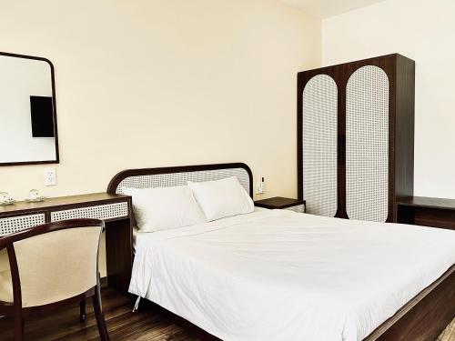 a bedroom with a bed and a desk with a mirror at Han Riverine Hotel & Cafeteria DaNang in Danang