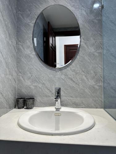 a bathroom sink with a round mirror above it at Han Riverine Hotel & Cafeteria DaNang in Danang